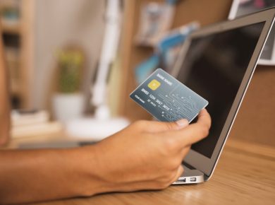 persona utilizando su tarjeta de crédito frente a laptop